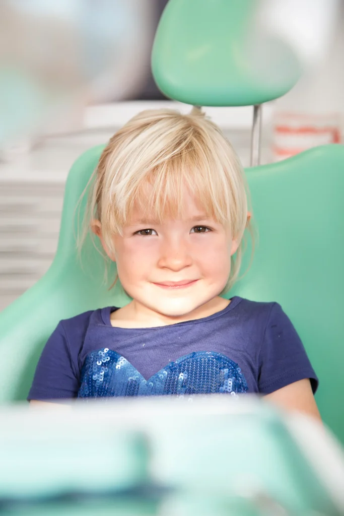 Bambina seduta tranquilla e sorridente sulla poltrona del dentista
