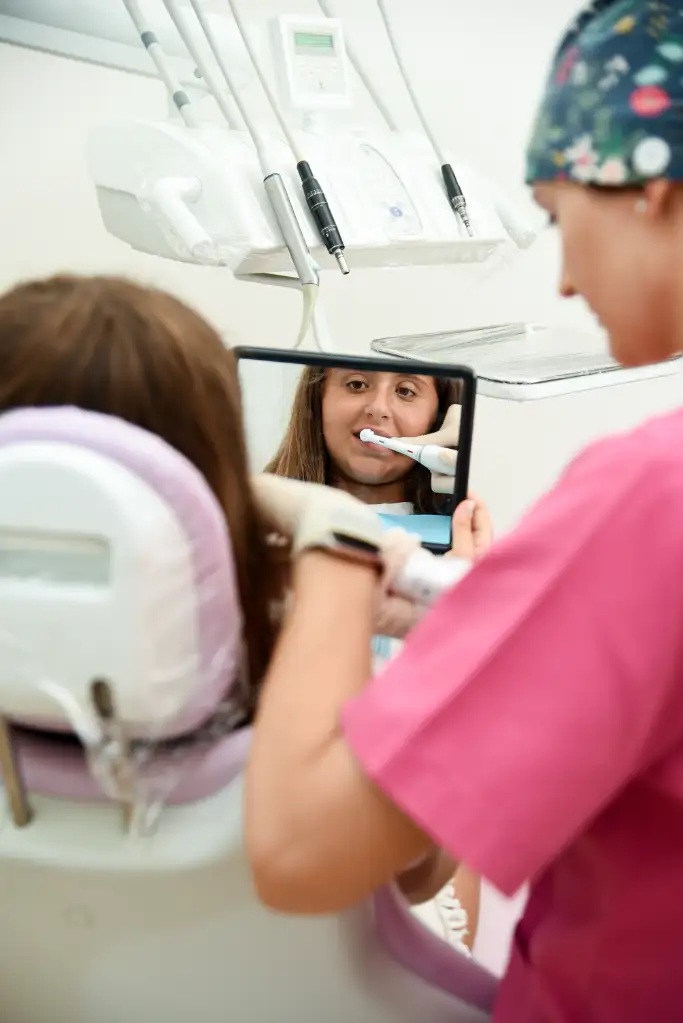 Una bambina si guarda i denti allo specchio mentre l'igienista dello Studio Solimei di Genova le esegue la pulizia